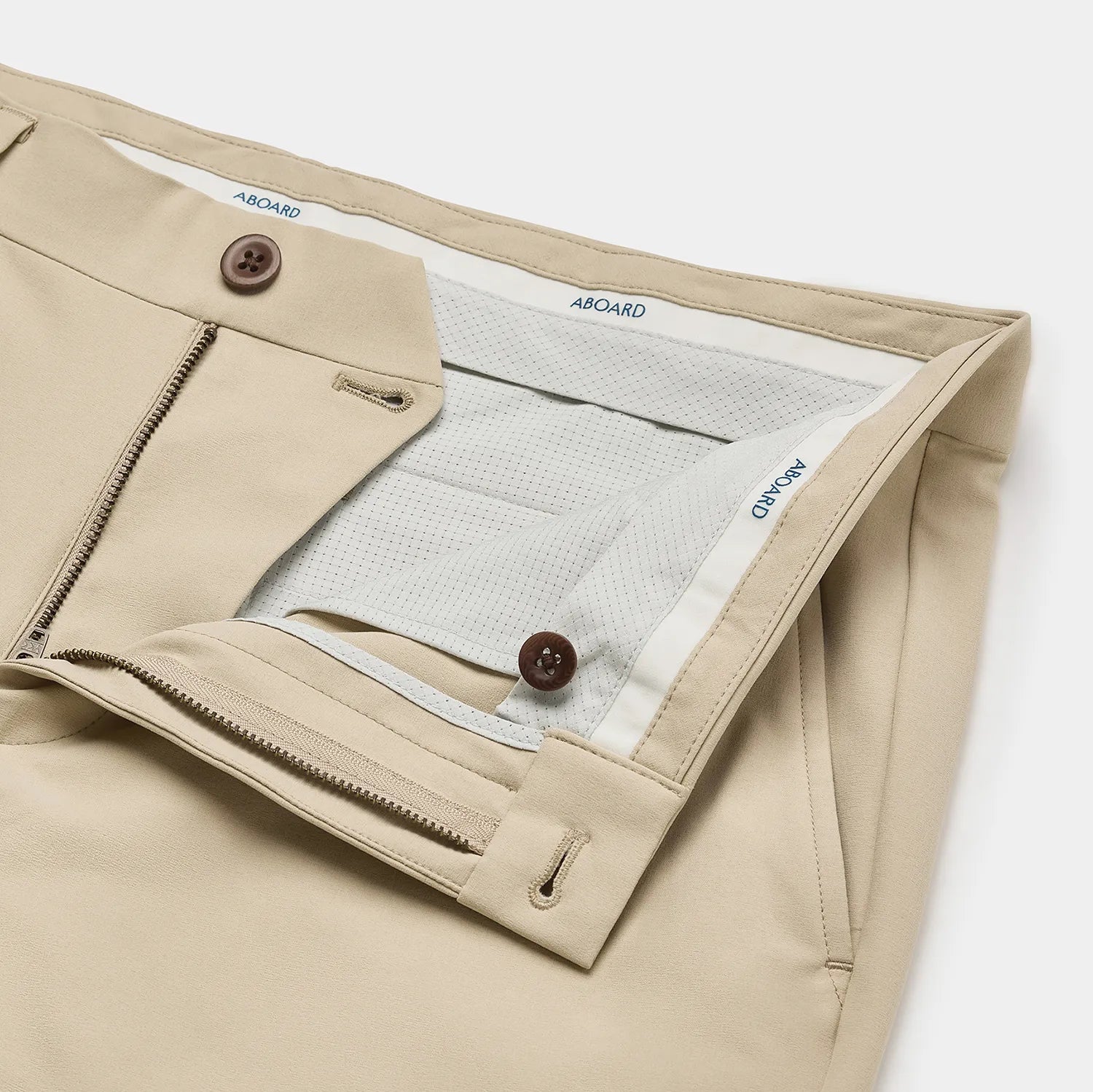 Close-up of the internal waist of Sand Positano Travel Chino, featuring luxury Corozo nut buttons and shirt gripper logo tape for added comfort and style.