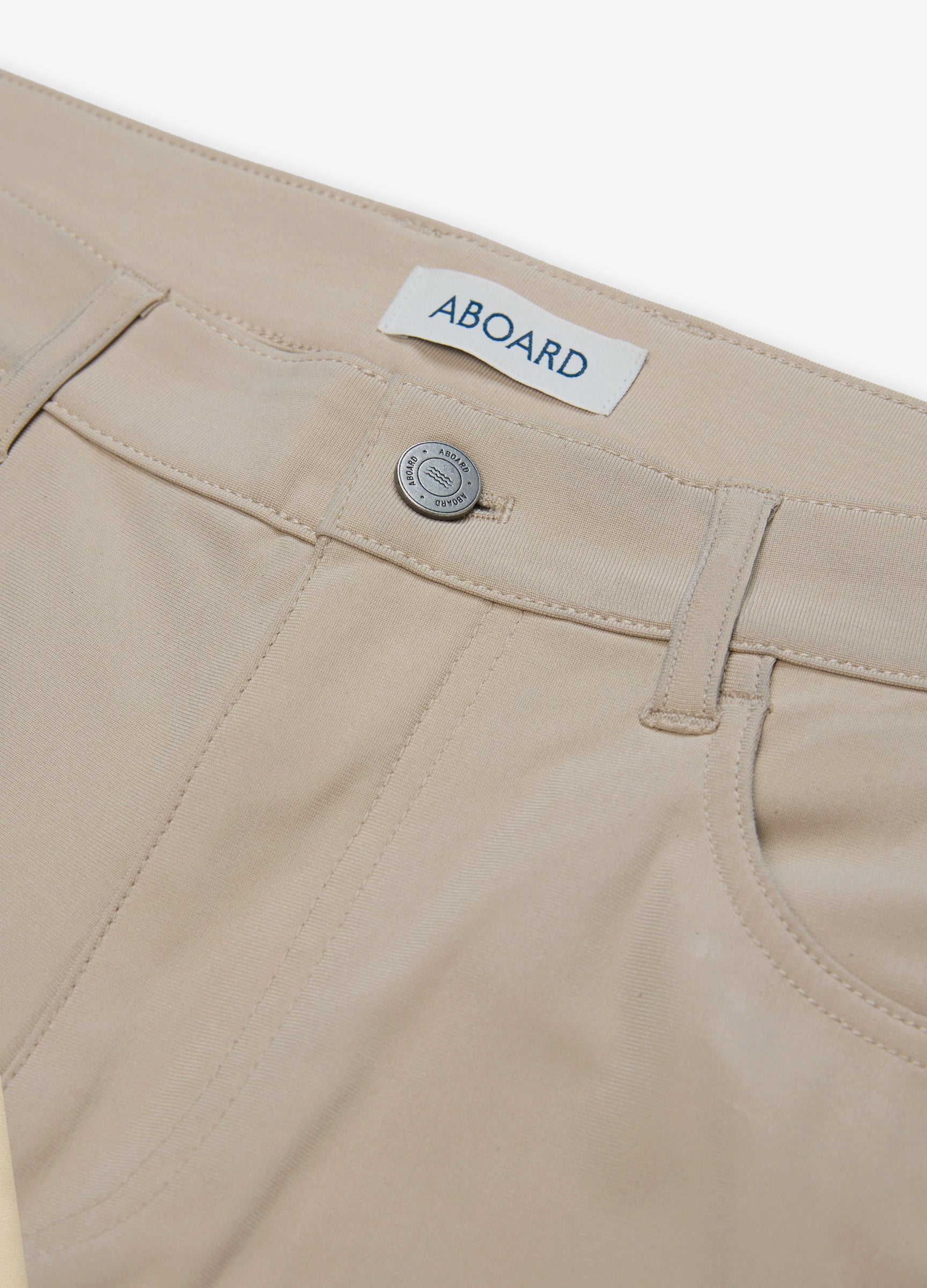 Four Seasons Travel Pant in Sand – Close-Up of Logo Metal Button & Premium Fabric #color_sand